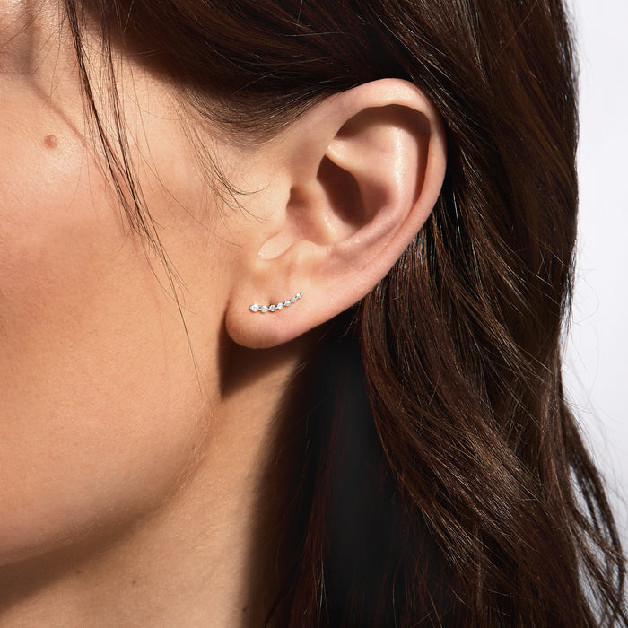 Sterling silver diamond ear climber on model ear, curved line of round stones