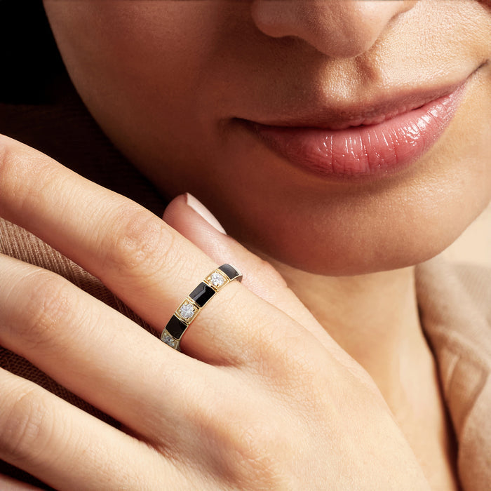 Black enamel and diamond ring on finger with gold-tone band