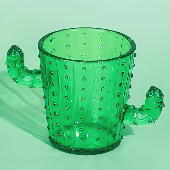 Front view of a green plastic cactus-shaped shot glass showcasing cactus flower handles with a mint green background