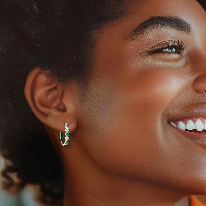 Green gemstone hoop earrings with clear diamond accents, worn on ear in side view