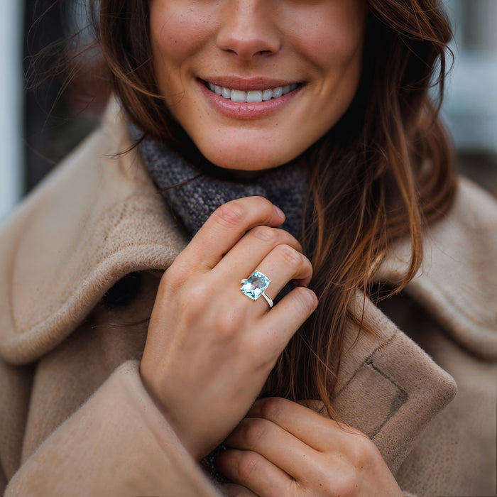 Sky blue cushion-cut topaz ring on finger with sterling silver band