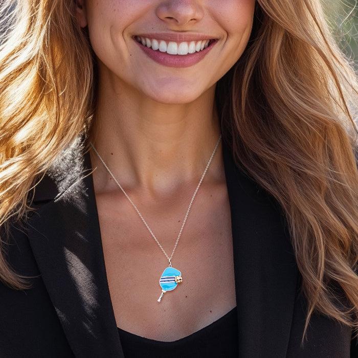 Blue enamel pickleball pendant necklace on sterling silver chain, shown worn on model