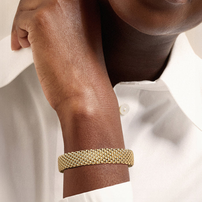 Gold beaded cuff bracelet on wrist, slim mesh band with small bar ends
