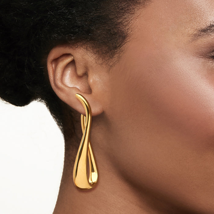 Twisted gold hoop earrings on ear, glossy teardrop loop with hinged closure