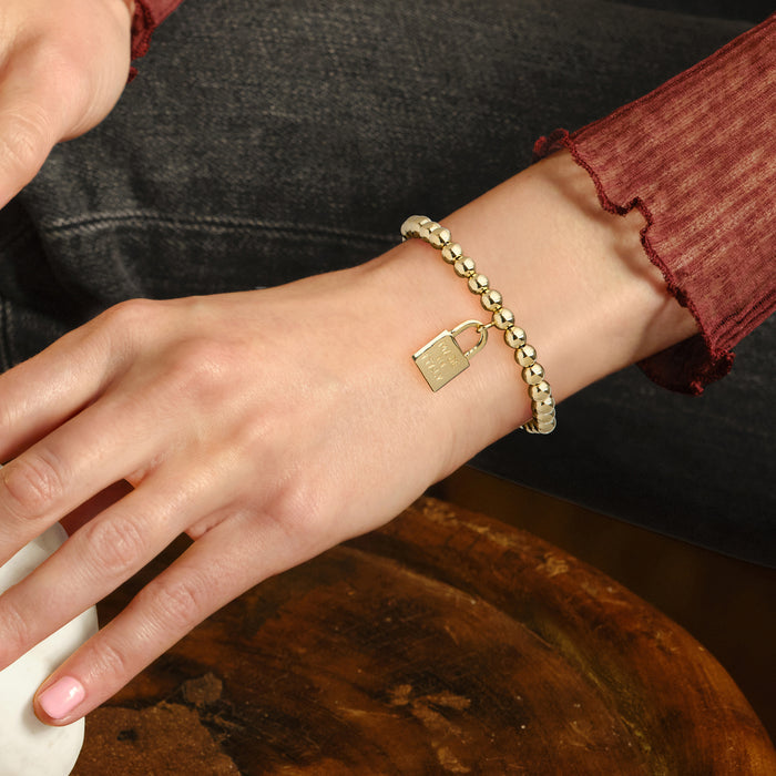 Gold over sterling bead stretch bracelet on wrist with small padlock charm, “Made in Italy”