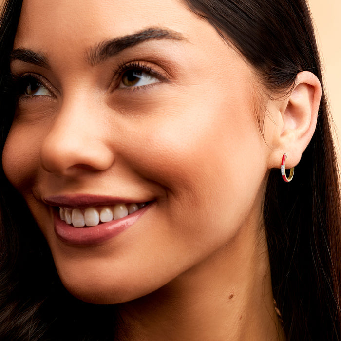Gold hoop earrings with red enamel and diamond accents on ear