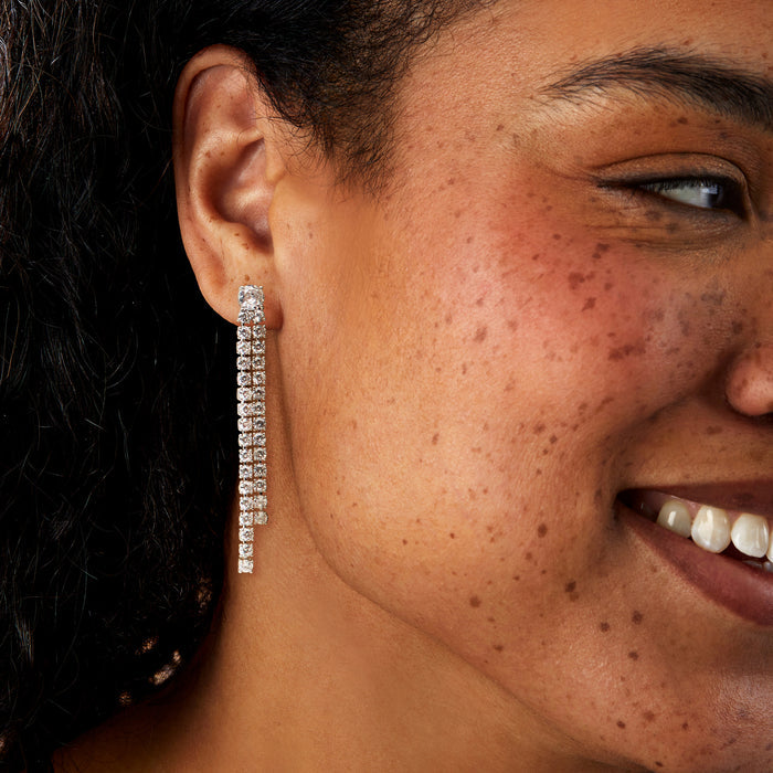 Rhodium-plated linear drop earrings with two-row clear CZ stones, worn on ear
